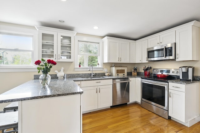 13 Juniper Ln, Cape Elizabeth, ME 04107 - kitchen with stainless steel appliances, a sink, a peninsula, white cabinetry, and light wood-style floors