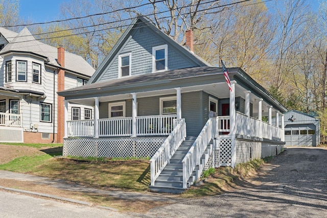 view of front facade featuring covered porch, a chimney, an outdoor structure, and a detached garage