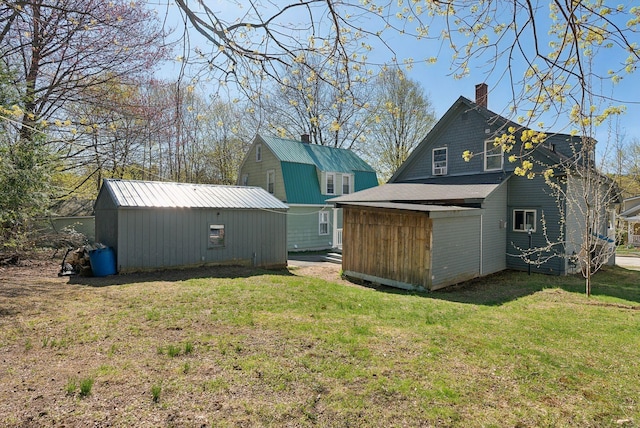 back of property featuring a lawn, an outdoor structure, and a chimney