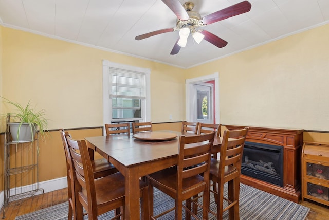 dining room featuring a ceiling fan, ornamental molding, a healthy amount of sunlight, and wood finished floors