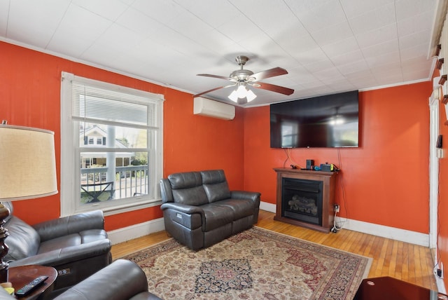 living area featuring crown molding, wood finished floors, a fireplace, ceiling fan, and a wall unit AC
