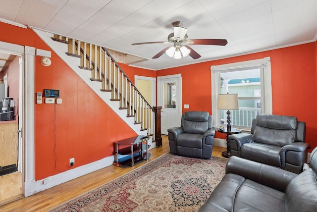 living room with ornamental molding, stairs, ceiling fan, and wood finished floors