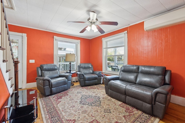 living room featuring a ceiling fan, crown molding, wood finished floors, an AC wall unit, and stairs