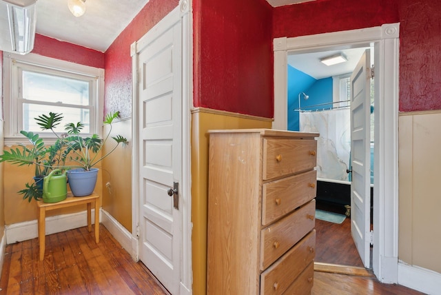 corridor featuring wood-type flooring and a wainscoted wall