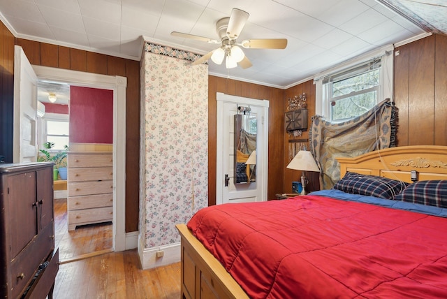 bedroom with baseboards, multiple windows, ornamental molding, and light wood-style flooring