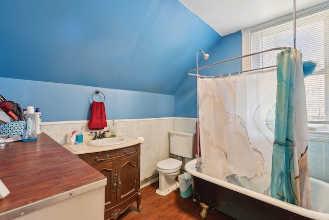 bathroom with tile walls, wood finished floors, vanity, toilet, and lofted ceiling