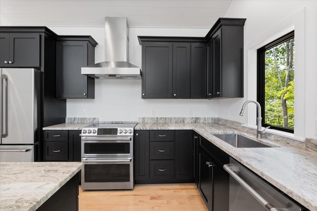 676 Sebago Rd, Sebago, ME 04029 - kitchen with appliances with stainless steel finishes, a sink, light wood finished floors, dark cabinetry, and wall chimney exhaust hood