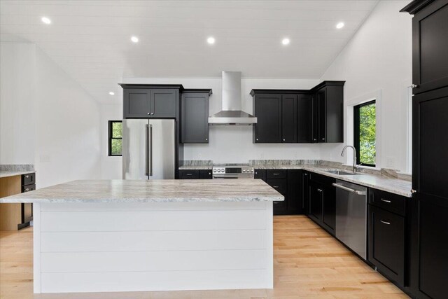 676 Sebago Rd, Sebago, ME 04029 - kitchen with a sink, light wood finished floors, wall chimney exhaust hood, stainless steel appliances, and a kitchen island