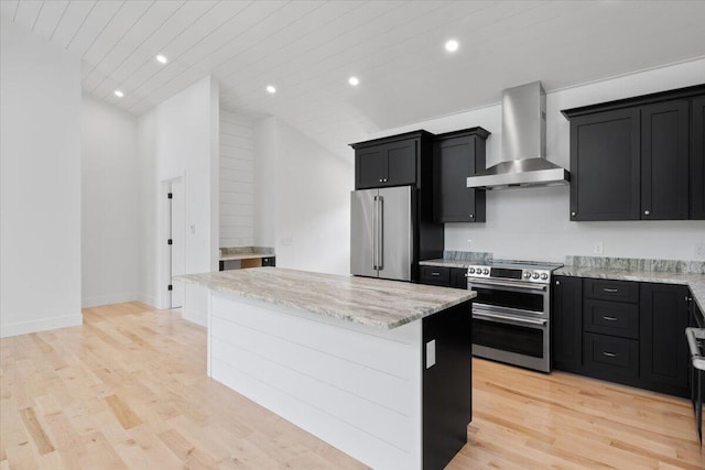 676 Sebago Rd, Sebago, ME 04029 - kitchen featuring wall chimney range hood, light wood-style floors, dark cabinets, a center island, and stainless steel appliances