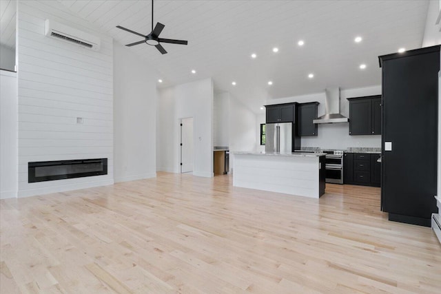 676 Sebago Rd, Sebago, ME 04029 - kitchen featuring an AC wall unit, wall chimney exhaust hood, a center island, stainless steel appliances, and open floor plan