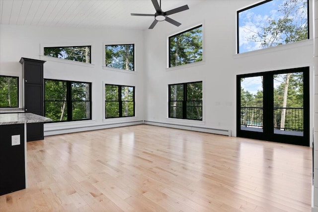 676 Sebago Rd, Sebago, ME 04029 - unfurnished living room with light wood-style floors, ceiling fan, a high ceiling, and baseboard heating