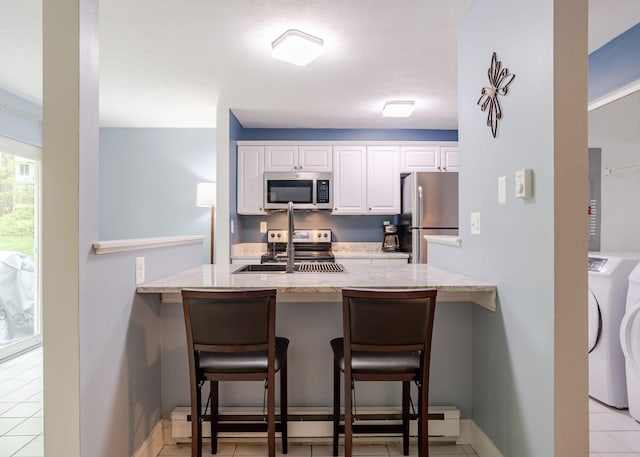 135 Portland Ave Unit 803, Old Orchard Beach, ME 04064 - kitchen with washing machine and clothes dryer, appliances with stainless steel finishes, a peninsula, a sink, and light stone countertops
