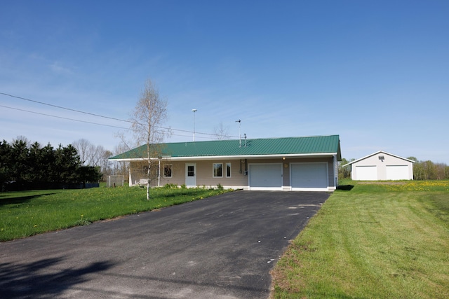 ranch-style home with a garage, driveway, a front lawn, and metal roof