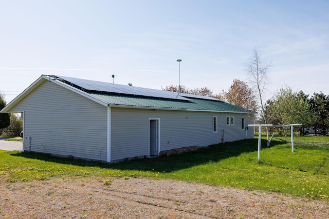 view of property exterior featuring a lawn, roof mounted solar panels, and metal roof
