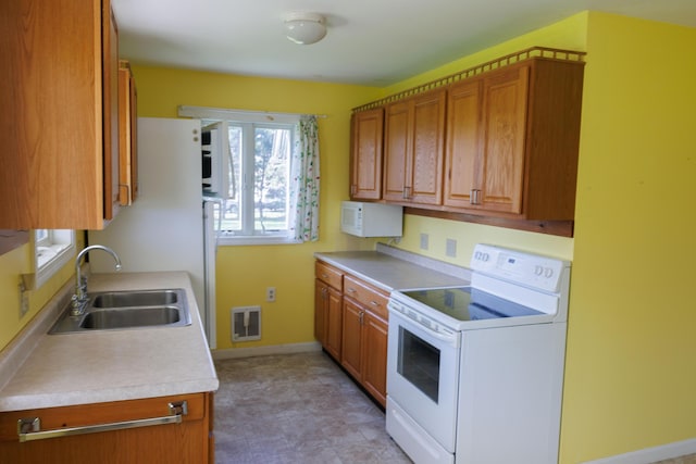 kitchen with white appliances, a sink, brown cabinets, and light countertops