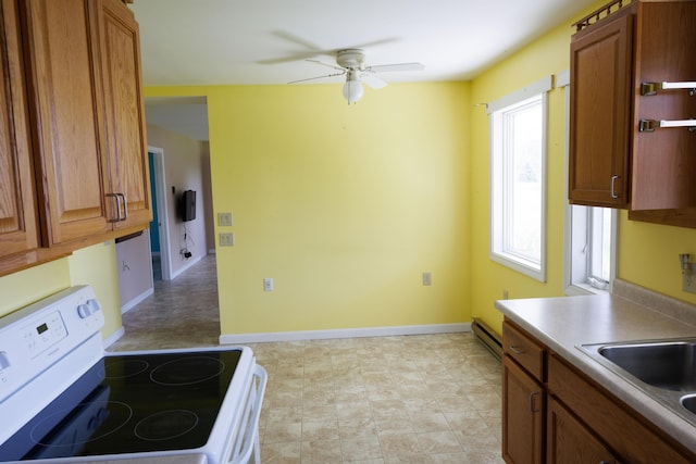 kitchen featuring white electric stove, a ceiling fan, a sink, brown cabinetry, and baseboards