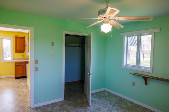 unfurnished bedroom with a closet, baseboards, and a ceiling fan
