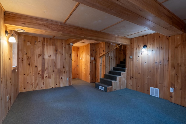 below grade area featuring wooden walls, carpet flooring, visible vents, and stairs