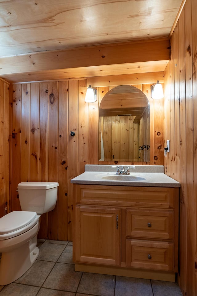 bathroom featuring toilet, wood walls, tile patterned flooring, and vanity