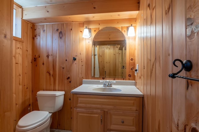 bathroom featuring wood walls, vanity, and toilet