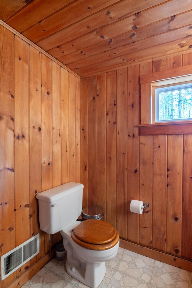 bathroom featuring visible vents, wooden walls, toilet, and wooden ceiling