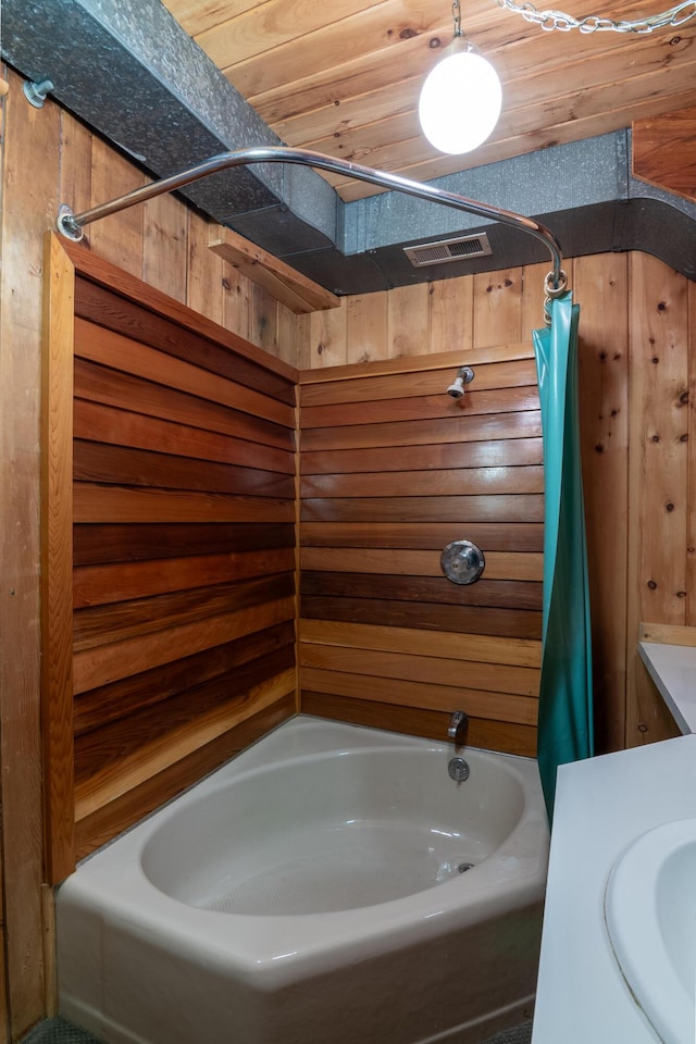 full bath featuring visible vents, a sink, shower / bathtub combination with curtain, and wood walls
