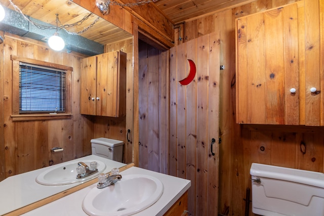 bathroom with wooden ceiling, wood walls, vanity, and toilet