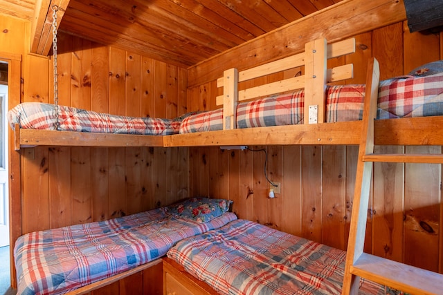 carpeted bedroom featuring wooden walls and wood ceiling