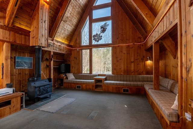 unfurnished living room with wooden walls, carpet floors, high vaulted ceiling, wooden ceiling, and beamed ceiling