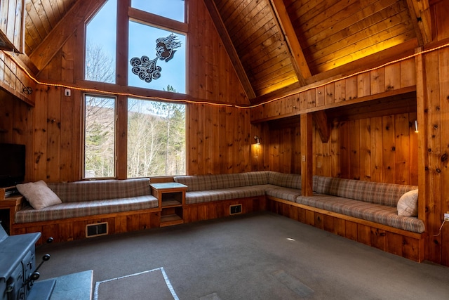 interior space with beam ceiling, high vaulted ceiling, wooden ceiling, wooden walls, and carpet