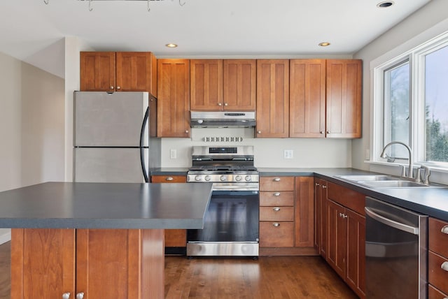 27 Rein Rd, Saint George, ME 04859 - kitchen featuring brown cabinetry, dark wood-style flooring, a sink, under cabinet range hood, and stainless steel appliances