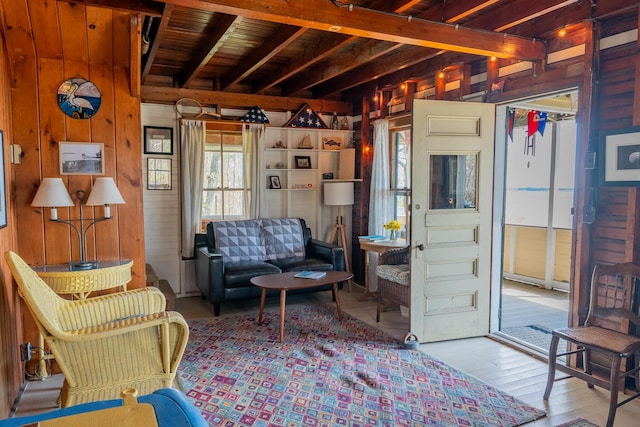 sitting room with wooden walls, wood finished floors, and beam ceiling