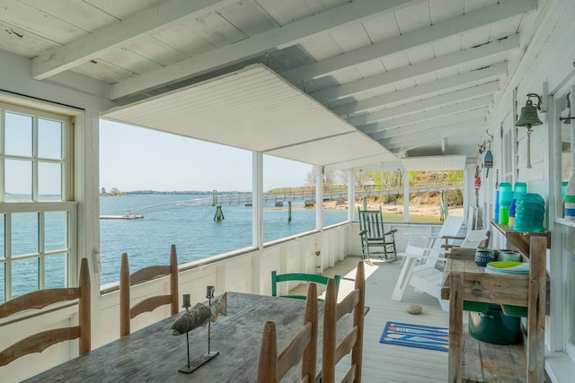 sunroom featuring beam ceiling and a water view