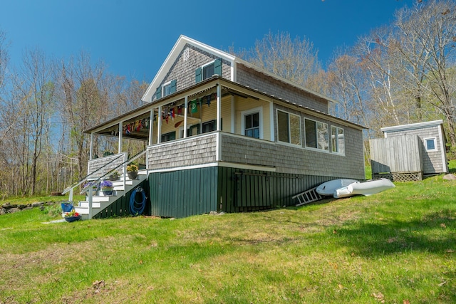 view of front of home featuring a front yard, stairway, a storage unit, and an outbuilding