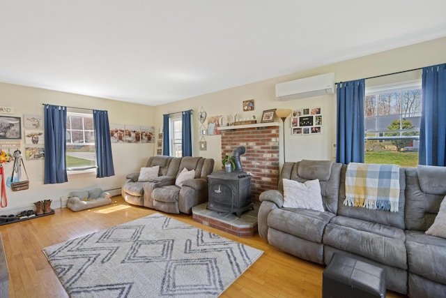 living room with an AC wall unit, a baseboard heating unit, wood finished floors, and a wood stove