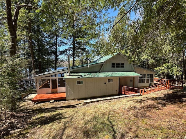 rear view of house featuring a wooden deck, metal roof, and a sunroom