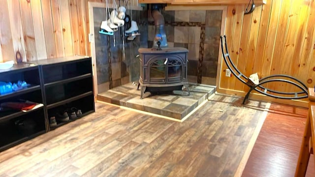 room details with wooden walls, a wood stove, and wood finished floors