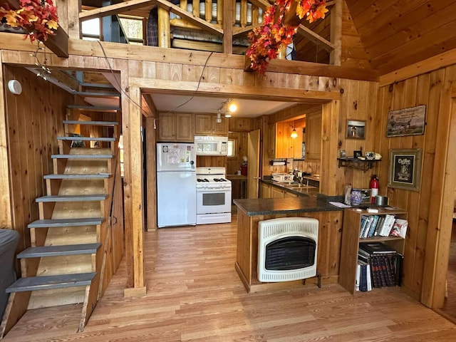 kitchen with dark countertops, a peninsula, wooden walls, heating unit, and white appliances