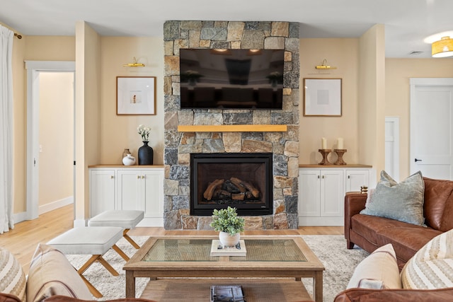 living area with light wood-style floors, a fireplace, and baseboards