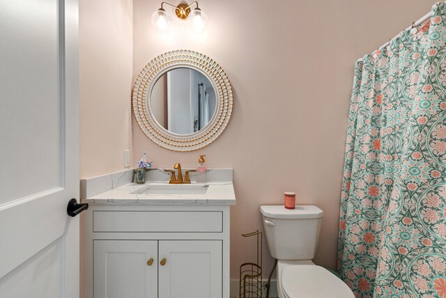 bathroom featuring toilet, vanity, and a shower with curtain