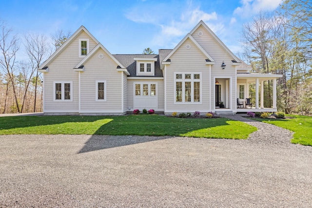 view of front of house featuring covered porch, a front lawn, and roof with shingles