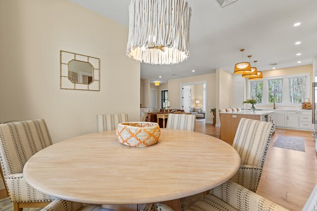 dining room with light wood finished floors, a chandelier, and recessed lighting