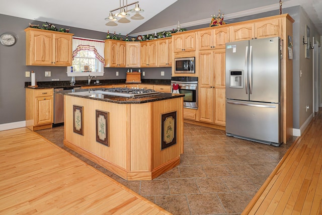 kitchen with baseboards, appliances with stainless steel finishes, lofted ceiling, and light brown cabinetry
