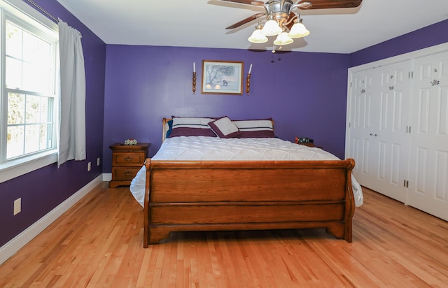 bedroom featuring baseboards, light wood-style flooring, ceiling fan, and a closet
