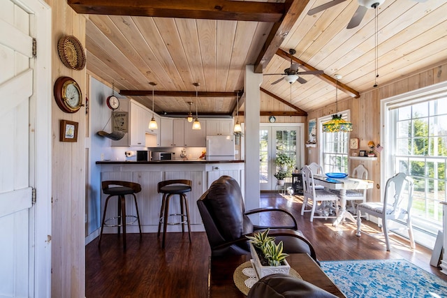 living area with wooden ceiling, ceiling fan, wood walls, and dark wood finished floors