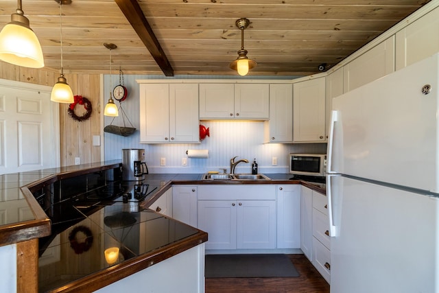 kitchen with freestanding refrigerator, wood ceiling, a sink, white cabinetry, and stainless steel microwave