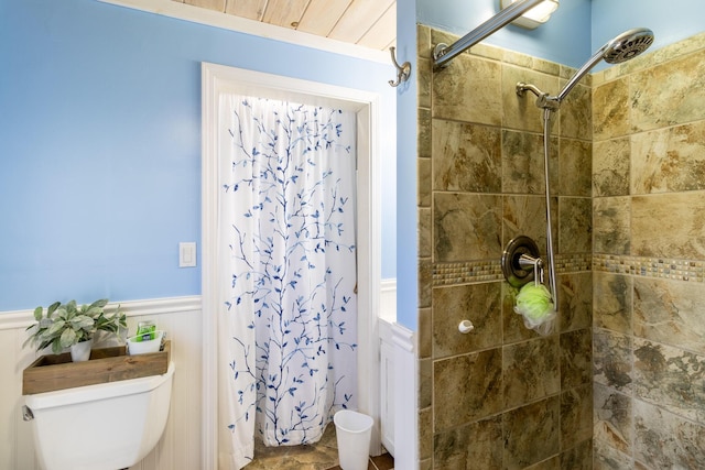 full bath with wainscoting, toilet, and tiled shower