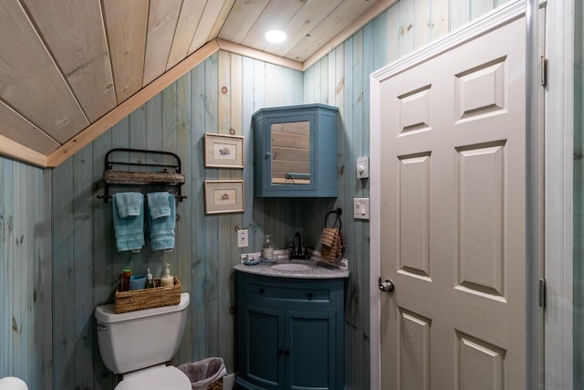 bathroom featuring toilet, wood ceiling, wooden walls, vaulted ceiling, and vanity