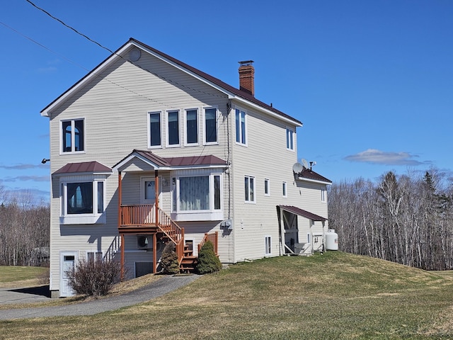 view of front of home featuring a standing seam roof, a front yard, a chimney, and metal roof