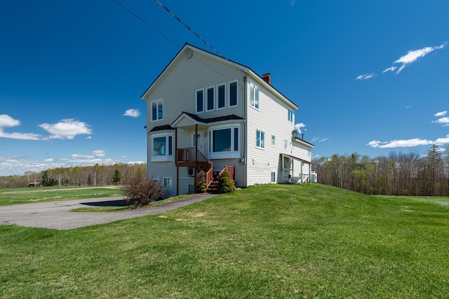 rear view of property featuring a lawn and a chimney